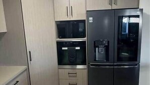 A compact kitchen with light-colored cabinets, a black refrigerator, and a microwave. - That 70s House - 5 bedroom of comfort and history (Ayr)