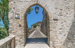 Um arco de pedra que dá acesso a uma escadaria.