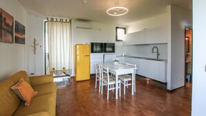 Een ruimtelijk ingerichte leefruimte met kitchenette, een eethoek en een bank.