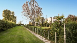 Een verzorgd tuinpad dat leidt naar een modern huis met een witte gevel, omringd door weelderige begroeiing en een heldere lucht.