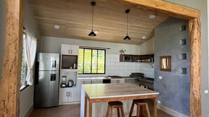 Una cocina moderna con vigas de madera, una isla central y un amplio ventanal.