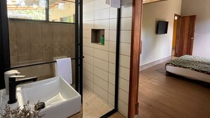 Un baño moderno con un espejo grande, un lavamanos blanco y una zona de ducha.