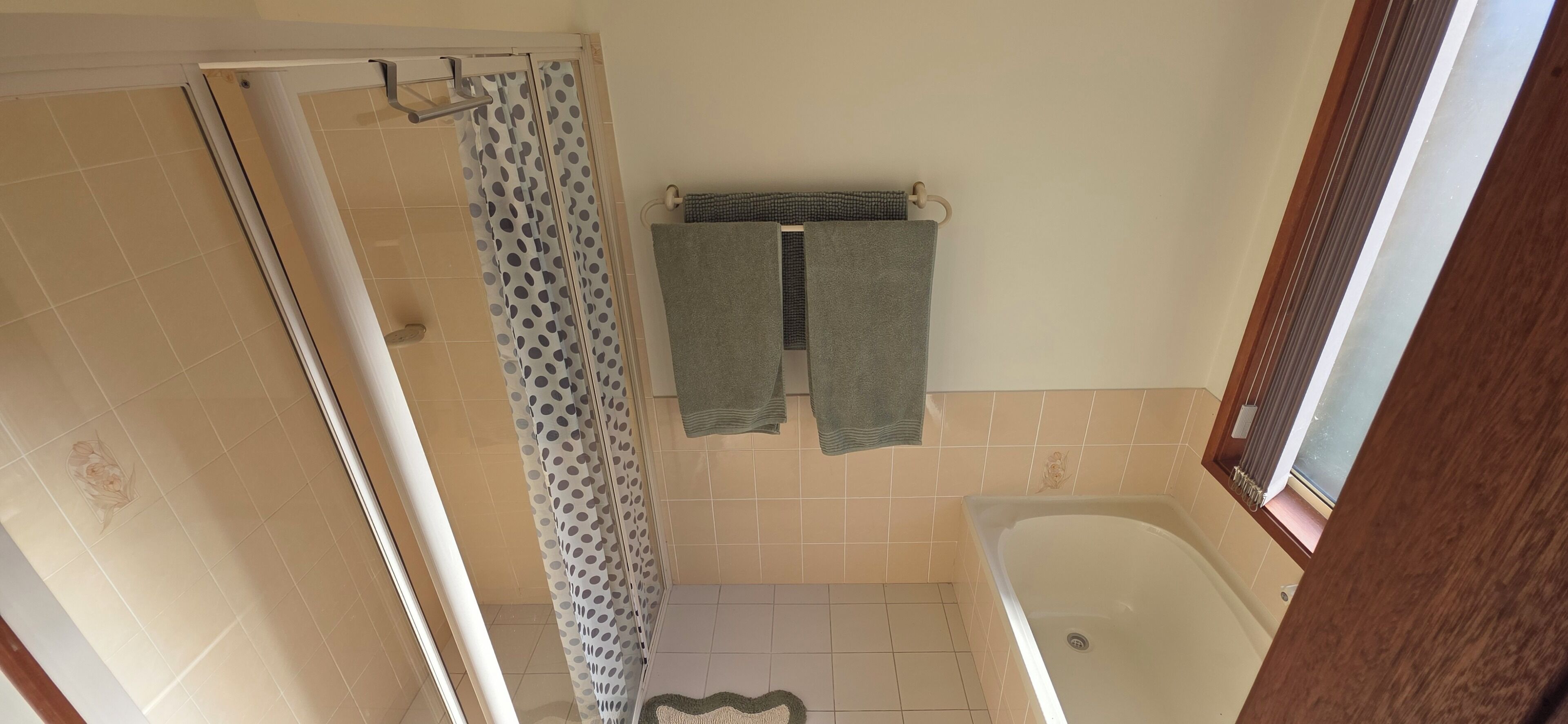 A bathroom with a shower, a bathtub, and a towel rack with two towels.