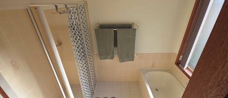 A bathroom with a shower, a bathtub, and a towel rack with two towels.