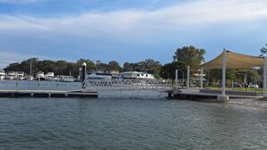 A marina with boats docked, a pedestrian bridge, and a canopy structure. - Skippers By The Bay - Lemon Tree Passage (Lemon Tree Passage)