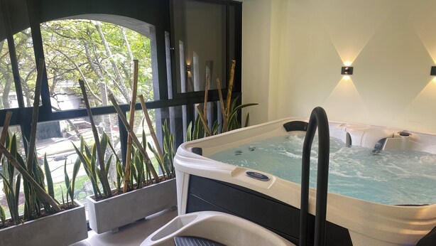 A modern spa area with a hot tub, a seating area, and large windows overlooking a garden. - RYO 74B 7TH FLOOR VIP (Medellín)