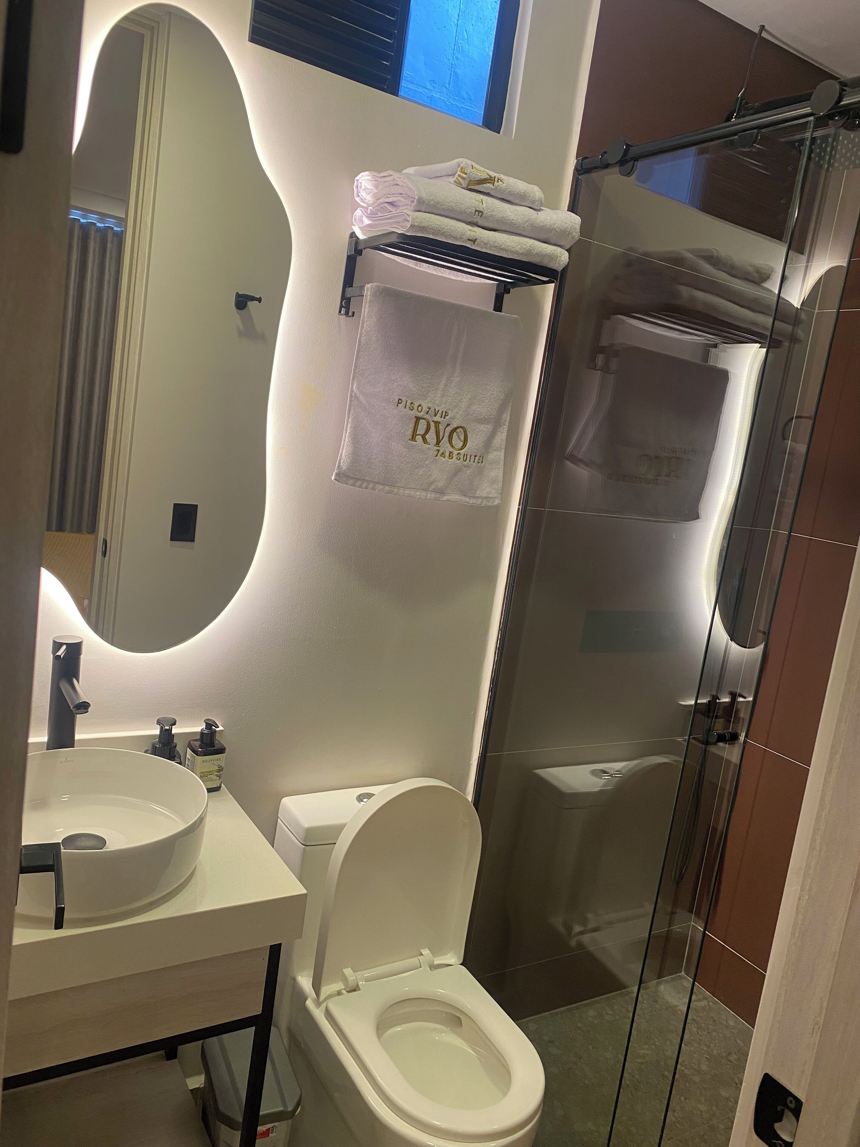 A modern bathroom with a white sink, a toilet, and a glass-enclosed shower.