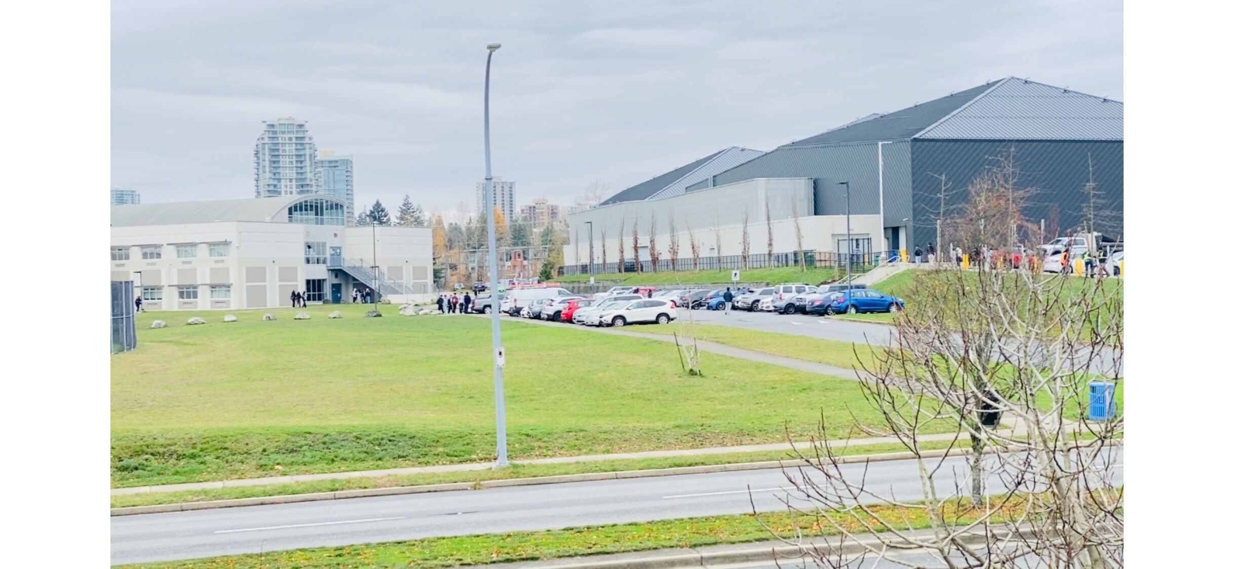 Un estacionamiento con coches, césped y un edificio de techo plano.