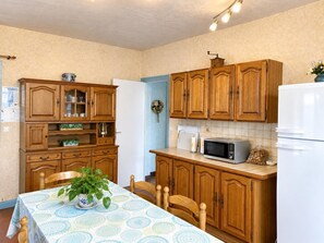 A kitchen with wooden cabinets, a microwave, and a refrigerator. - CHEZ MATHIEU - CHESTRES (CHESTRES)