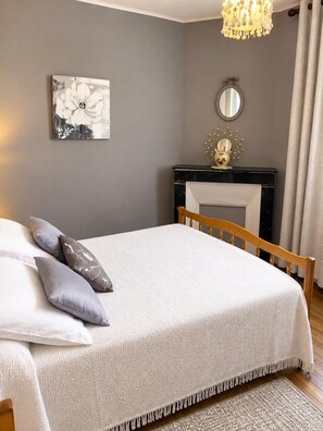 Un dormitorio con cama, chimenea, espejo y candelabro.