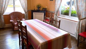 Un comedor con una mesa larga, sillas, chimenea y cortinas.