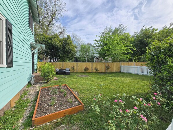 A backyard with a raised garden bed, a wooden fence, and a lawn.