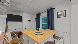 A compact kitchen with a wooden table, white chairs, a small dining table, and a ceiling fan. - Historic Downtown New Bern Retreat - Pet Friendly (New Bern)