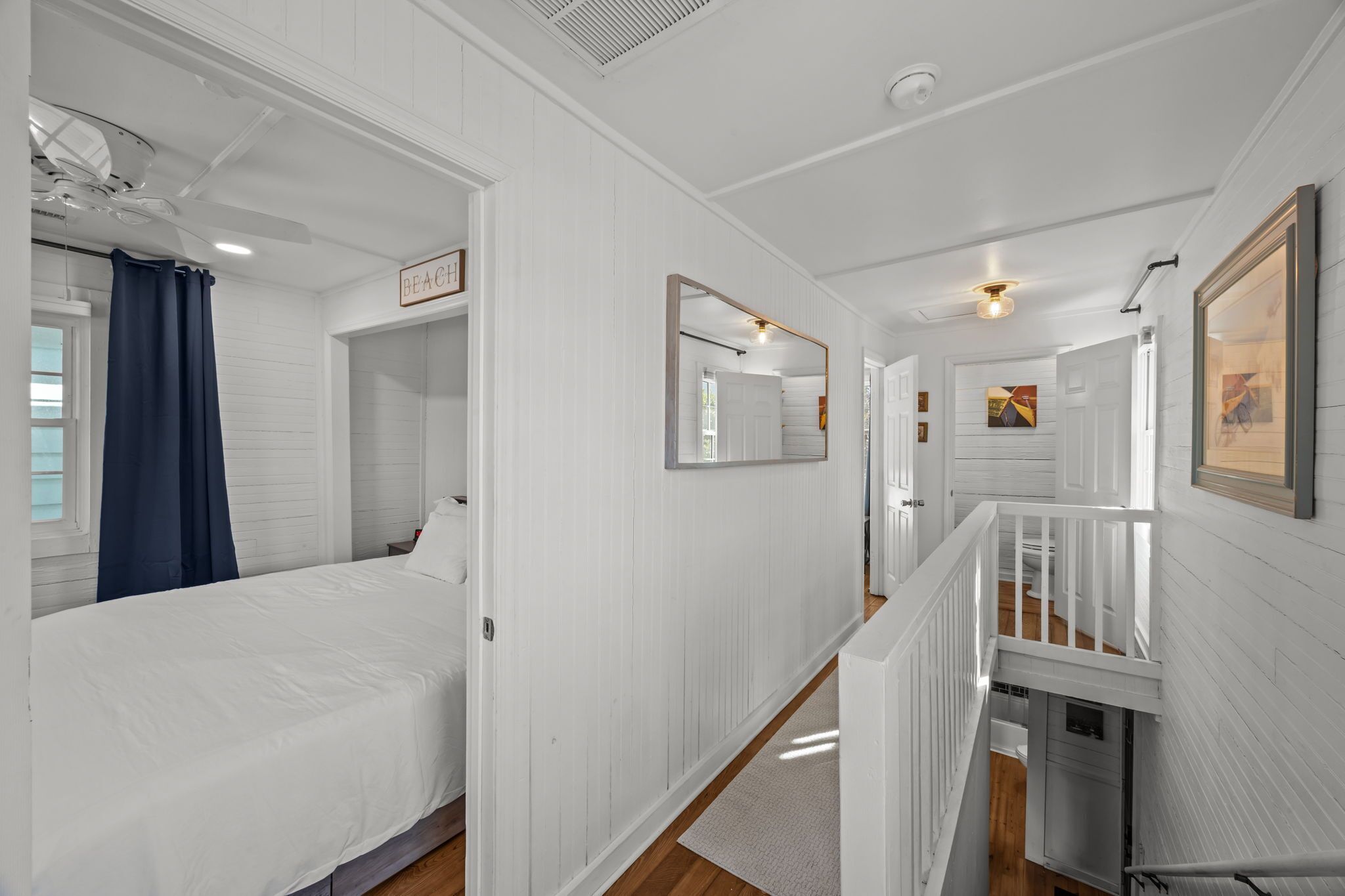 A hotel room with a bed, a bathroom, a staircase, and a hallway.