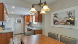 Cozinha moderna com armários de madeira, bancada de granito e área de jantar com mesa e cadeiras de madeira.