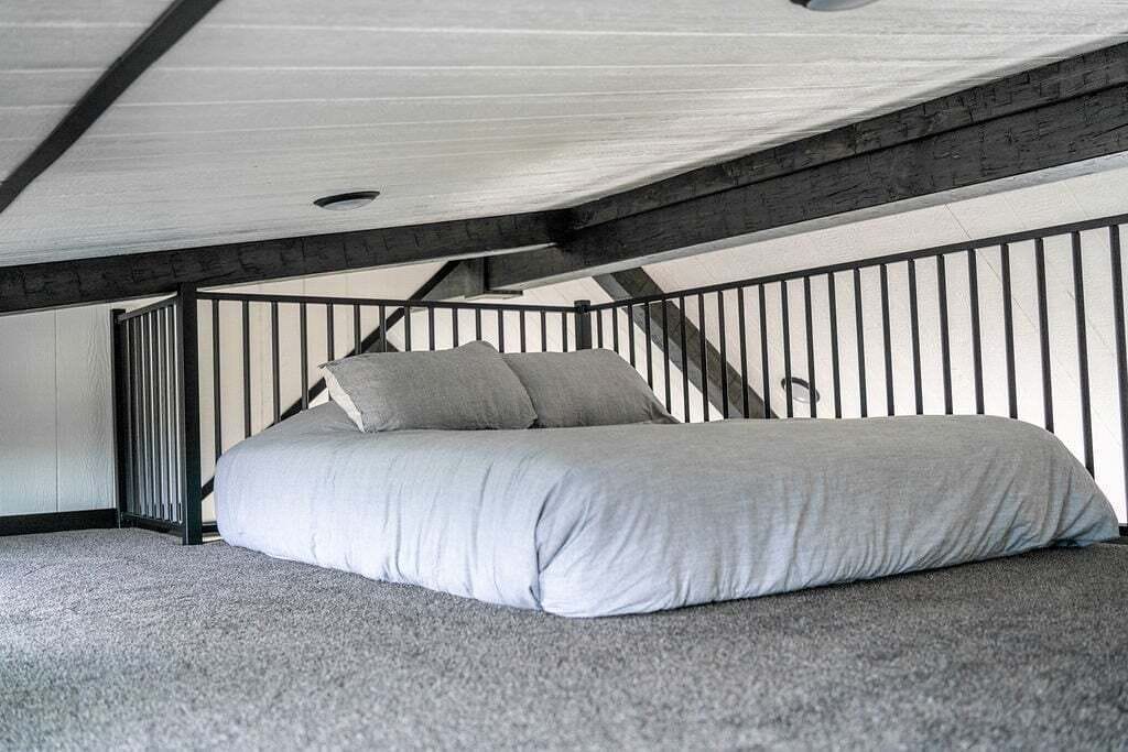 Une chambre à coucher avec un lit, une fenêtre et un escalier.