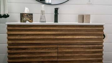 A bathroom vanity with a wooden finish, a mirror above it, and a white countertop.