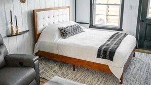 A bedroom with a wooden bed, a patterned pillow, a woven rug, and a wall-mounted animal head decoration.