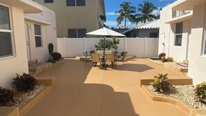 Un cortile con un tavolo e sedie, circondato da edifici con muri bianchi e finestre.