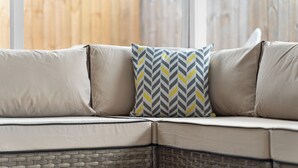 A beige sofa with a woven base and a patterned cushion. - Game Room Retreat • Fire Pit • 5 Min to Downtown (Mount Dora)