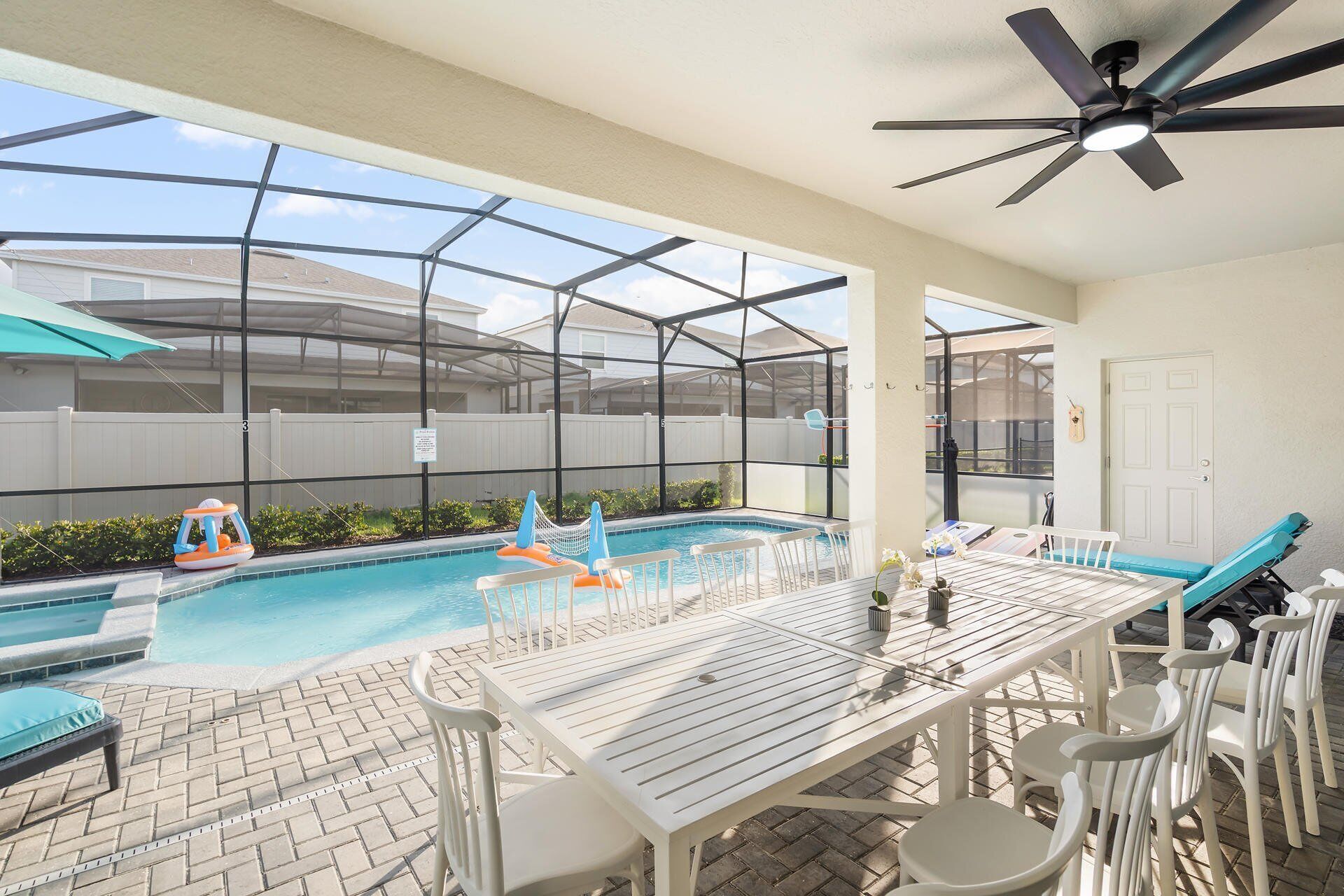 Ein Poolbereich mit überdachter Terrasse, einem Tisch und Stühlen sowie einem Deckenventilator.