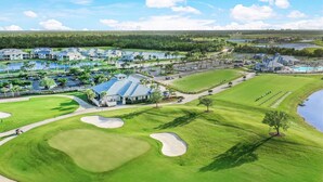 An aerial view of a golf course with a clubhouse, sand bunkers, and a water body. - Heritage Landing Golf and Country Club Vacation Condo (Punta Gorda)