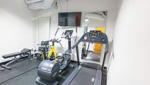 Ein Fitnessraum mit Laufband, Crosstrainer und Krafttrainingsgeräten.