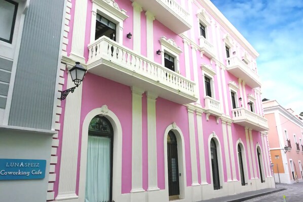 A pink building with white trim and balconies, labeled "LunaSpeiz Coworking Cafe." - Beachside Retreat with Pool - Sleeps 4 (San Juan)