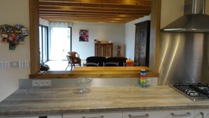 A kitchen with a wooden beam ceiling, a gas stove, a microwave, and a window.
