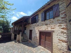 A rustic stone building with a wooden balcony and a set of stairs leading to the entrance. - 46G1553 - PRENDEIGNES (PRENDEIGNES)