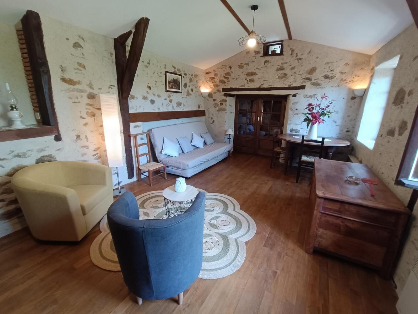 A cozy living room with a sofa, armchairs, a wooden coffee table, and a dining area with a table and chairs.