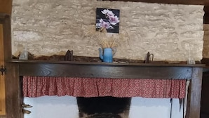 Pejs med baggrund af stenvæg, en dekorativ vase og en rød stribet gardin.