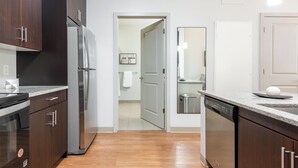 A modern kitchen with dark wood cabinets, stainless steel appliances, and a light-colored countertop. - Landing Furnished Apartments South End Stratford (Stratford)