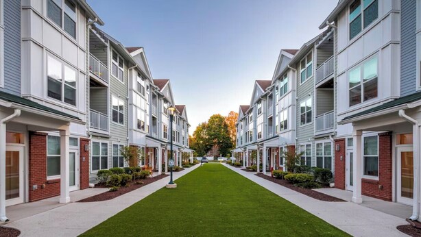 A row of townhouses with a central lawn, featuring a symmetrical design with brick accents and white siding. - Landing Furnished Apartments South End Stratford (Stratford)