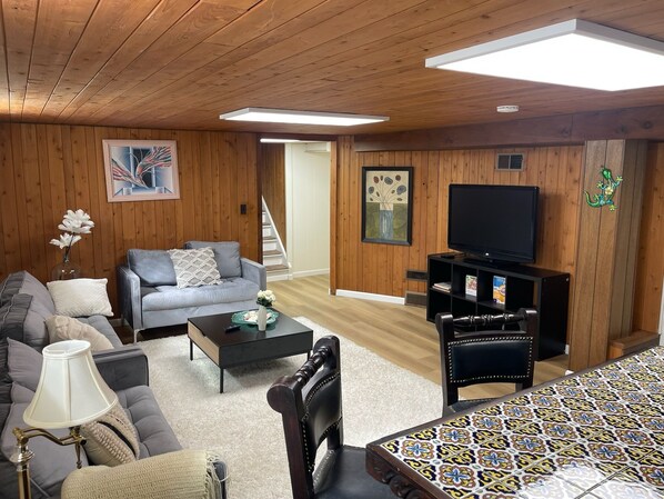 Sala de estar com sofá, mesa de centro, rack para TV e toalha de mesa estampada.