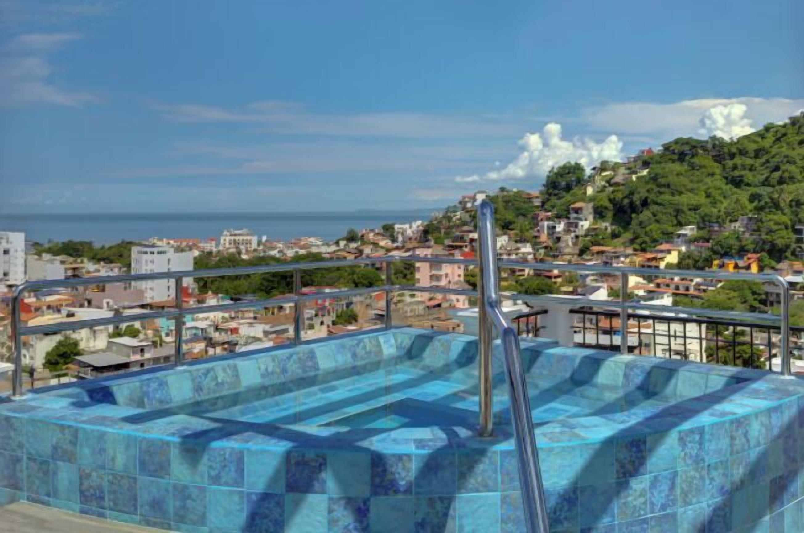 A rooftop pool with a view of a coastal cityscape.