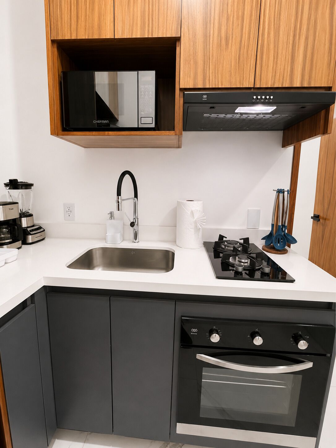 A modern kitchen with a stainless steel sink, a built-in microwave, a gas stove, and a built-in oven.