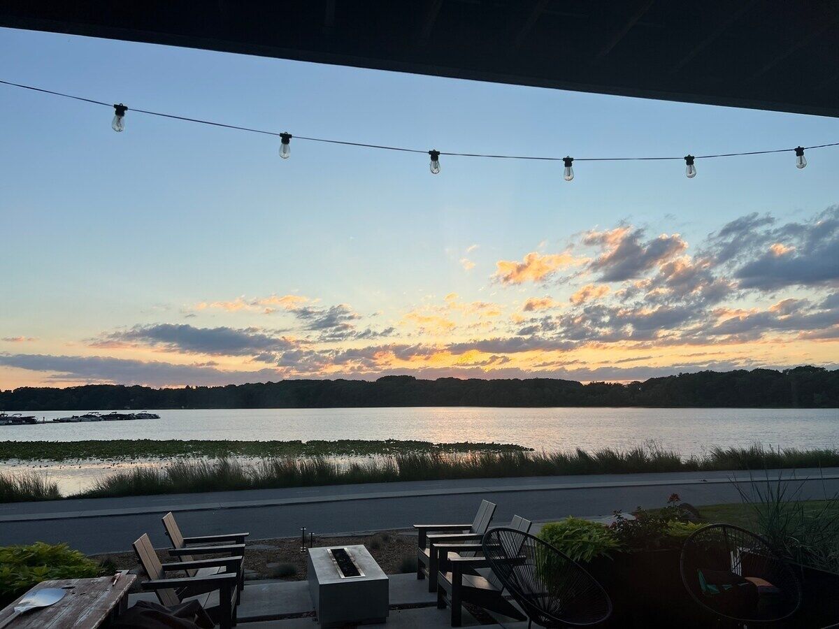 Een terras aan het meer met zitplaatsen buiten en een lichtslingering.