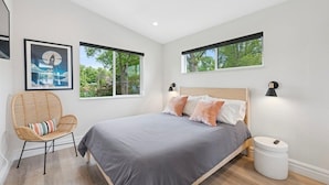 A modern bedroom with a bed, a chair, and two windows. - New! Modern lakeside retreat-hot tub-trails-kayak (La Porte)
