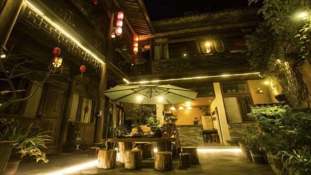 An outdoor dining area with a table and chairs, surrounded by potted plants and a wooden fence. - Tengchong Tangxi Homestay (Tengchong)