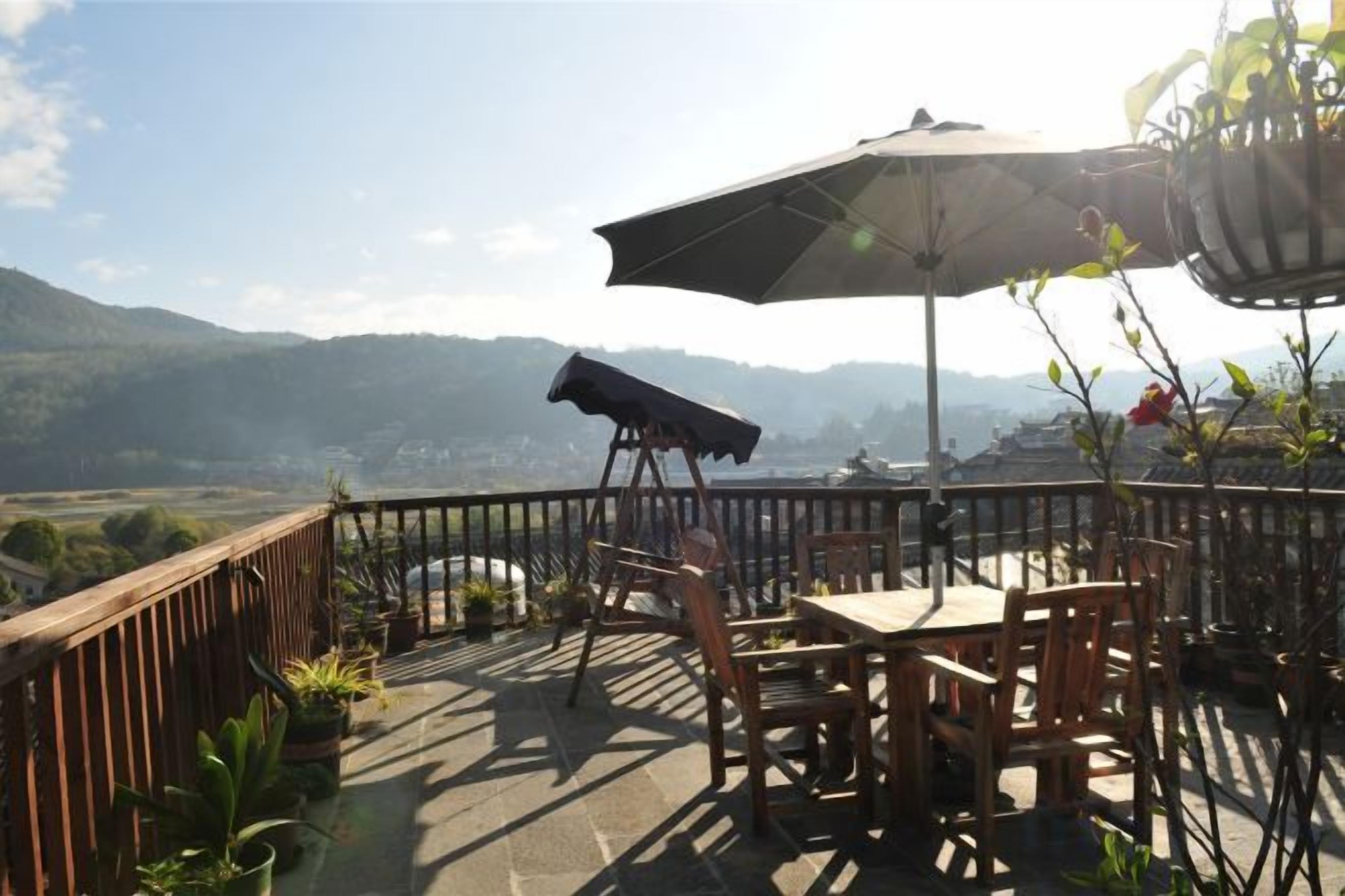 Una terraza con mesa y sillas, un sillón colgante y vistas a las montañas.