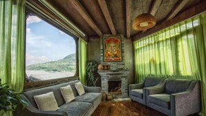 A cozy room with a sofa and armchairs, a fireplace, and a view of the outdoors. - Tengchong Tangxi Homestay (Tengchong)