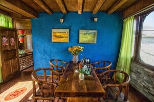 Un comedor con una mesa y sillas de madera, un jarrón con flores y dos cuadros en la pared.