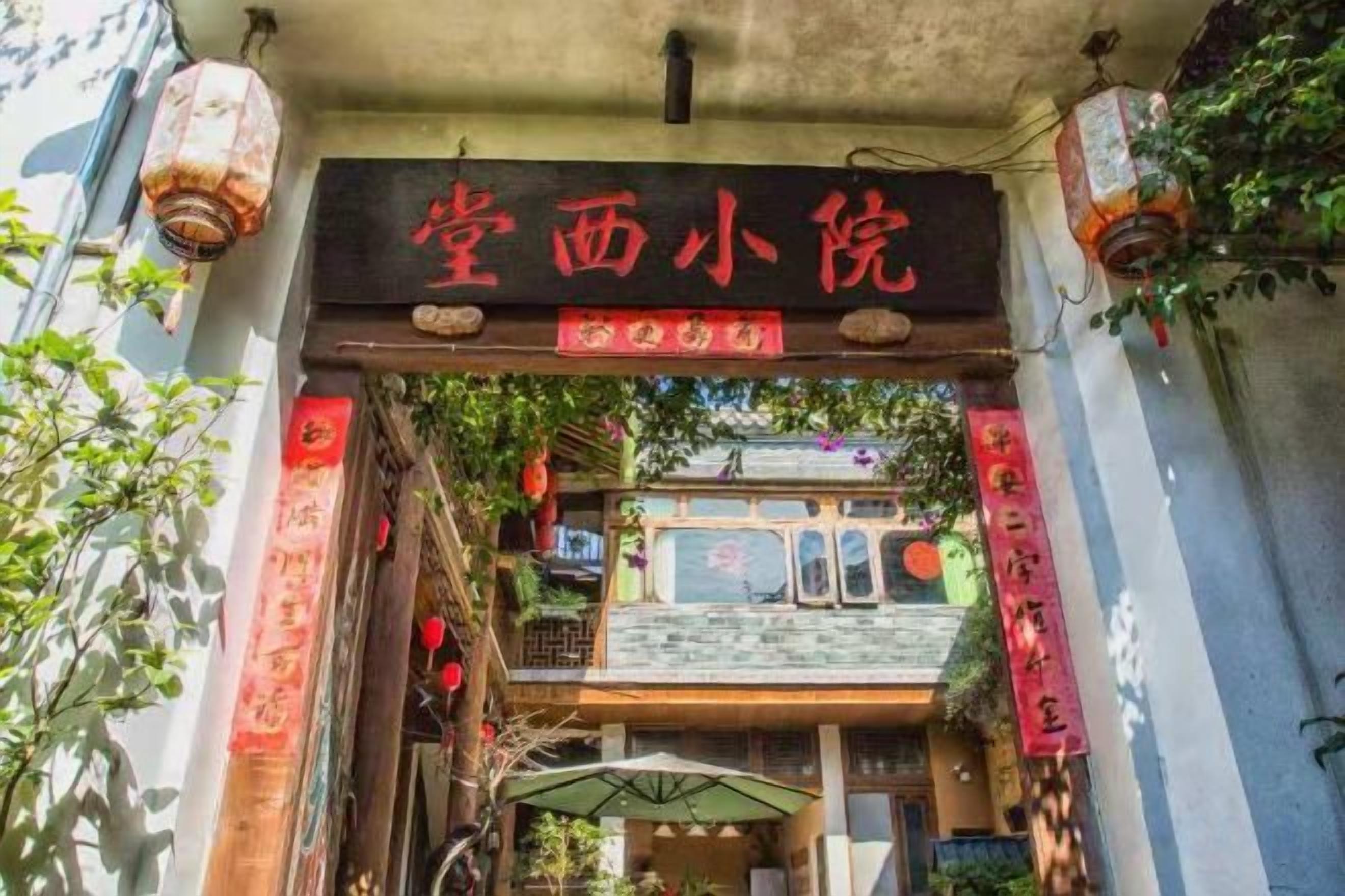 A traditional Chinese gate with red decorations and a sign above it.