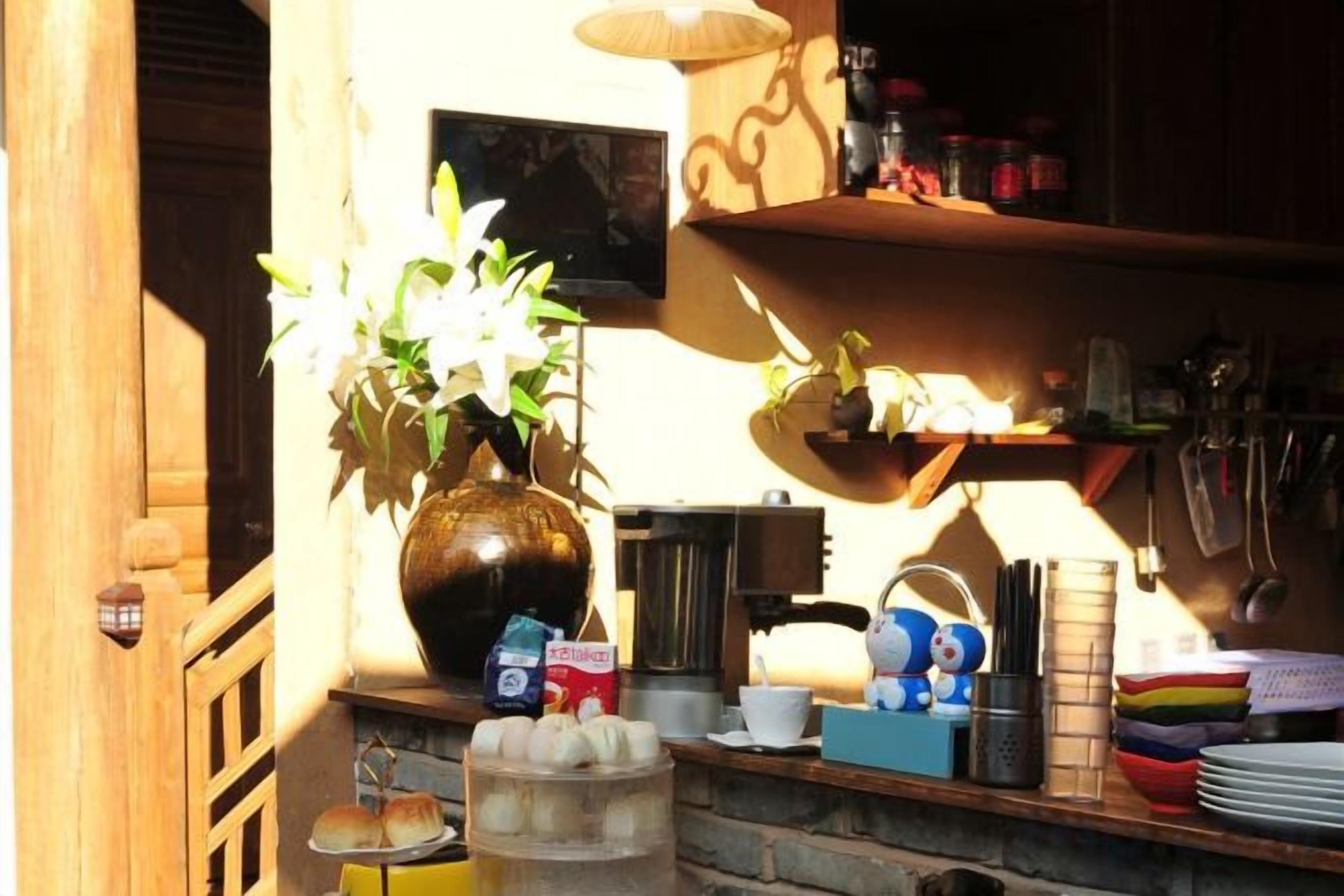 A kitchen with a vase of flowers, a coffee machine, and various kitchen utensils.