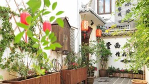 A traditional courtyard with wooden planters, red lanterns, and potted plants. - Tengchong Tangxi Homestay (Tengchong)