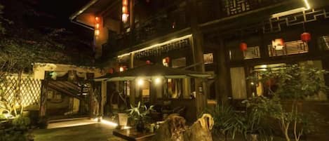 A traditional building with a courtyard, wooden furniture, and potted plants.