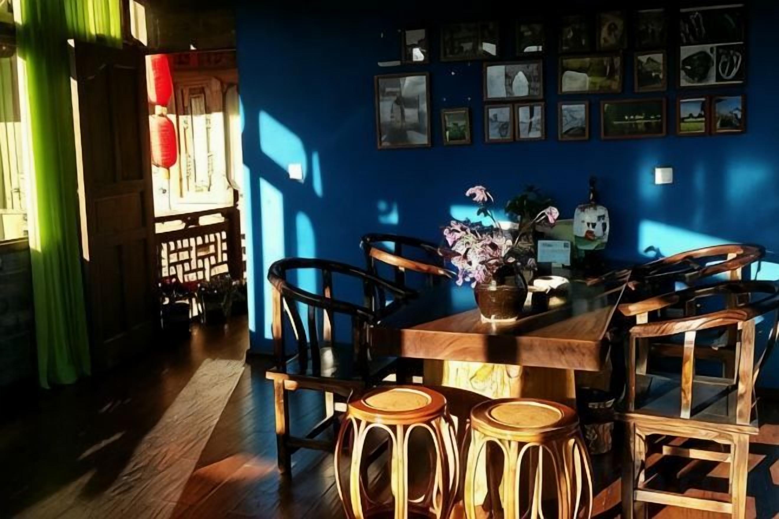 Un comedor con mesa y sillas de madera, un florero con flores y una pared con cuadros.