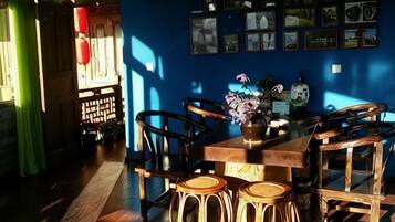 Un comedor con mesa y sillas de madera, un florero con flores y una pared con cuadros.