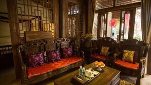 A traditional wooden room with a sofa set, a coffee table with a tray of pastries, and a decorative screen. - Tengchong Tangxi Homestay (Tengchong)